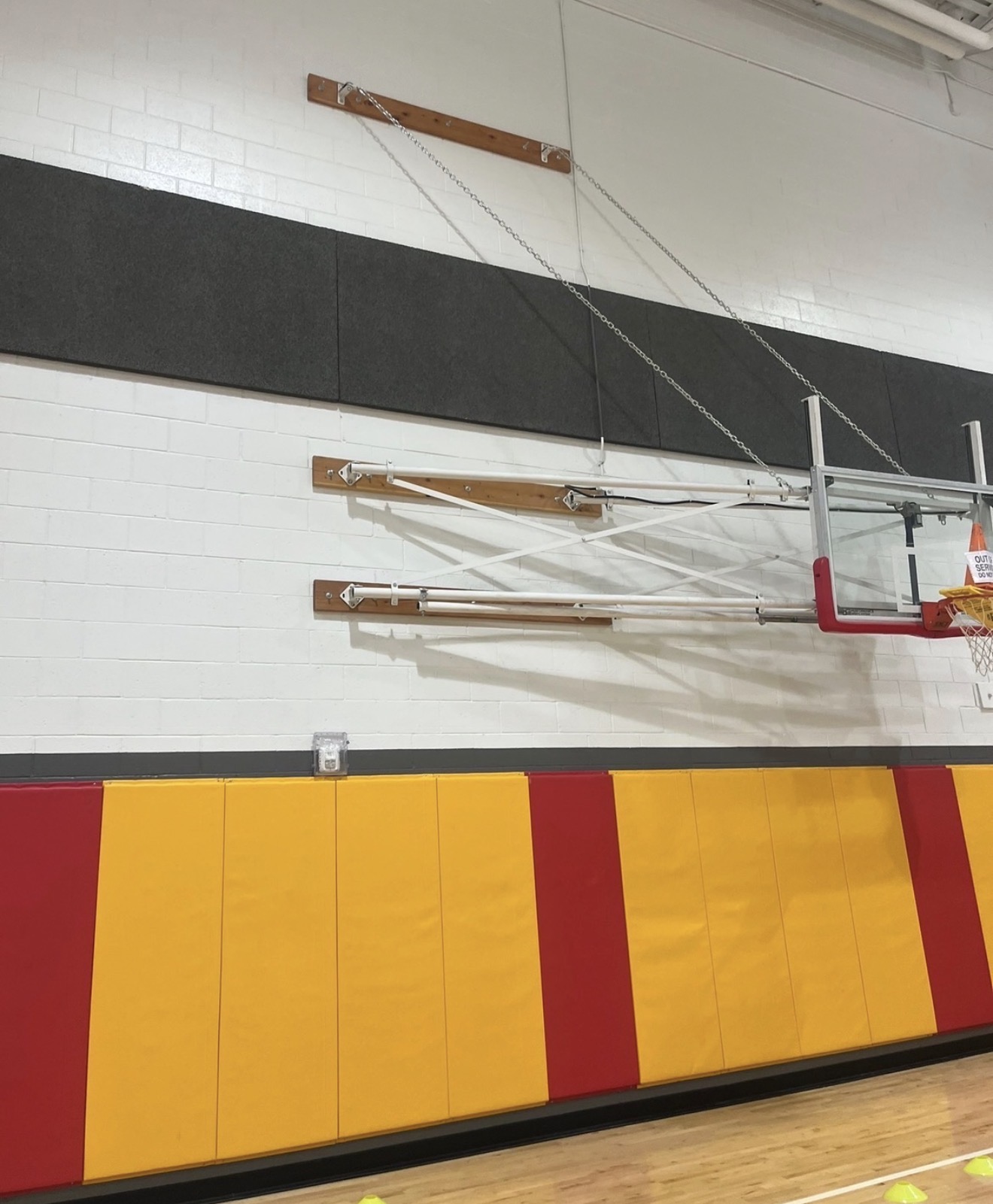 Aerial lift positioned under gymnasium ceiling for backboard adjustment