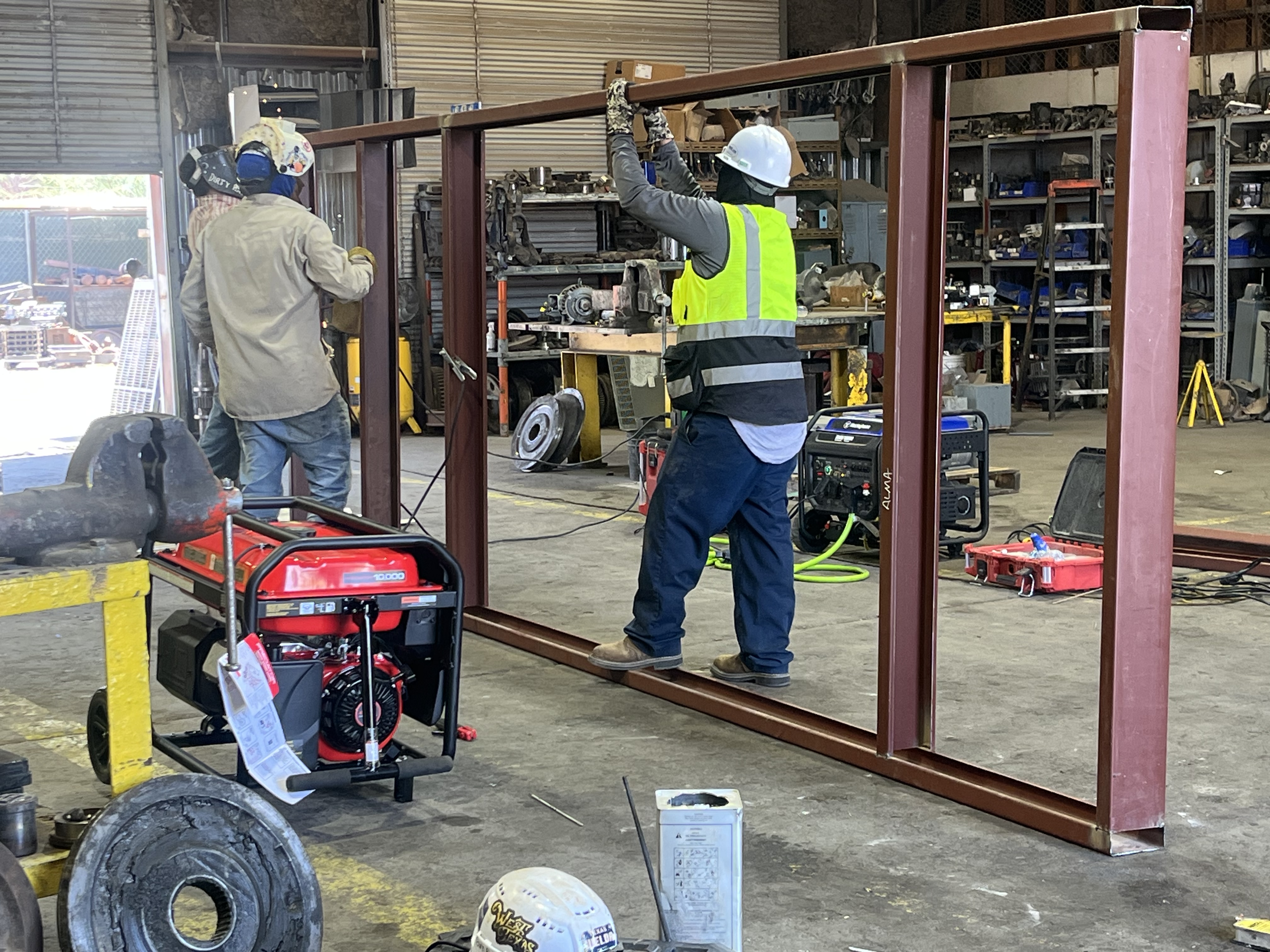 Two welders fabricating a custom structural steel frame in-shop
